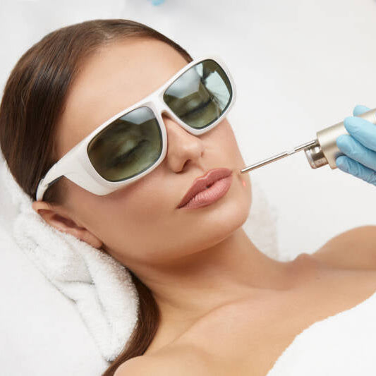 A woman receiving a Fotona 4D laser skin treatment from a professional in a medical setting.